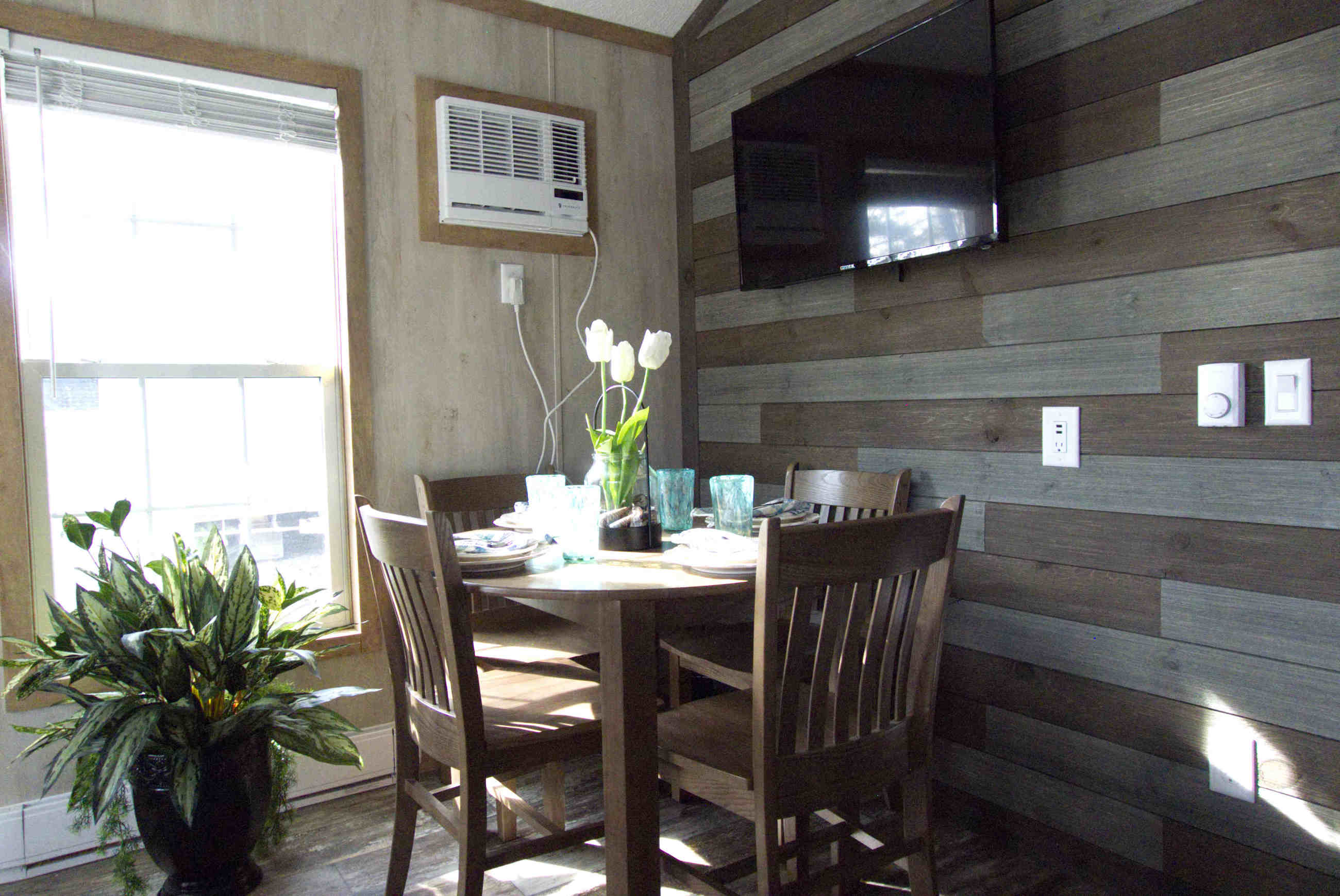 The cottages have a dining area with four chairs, a bench for two, and a TV.