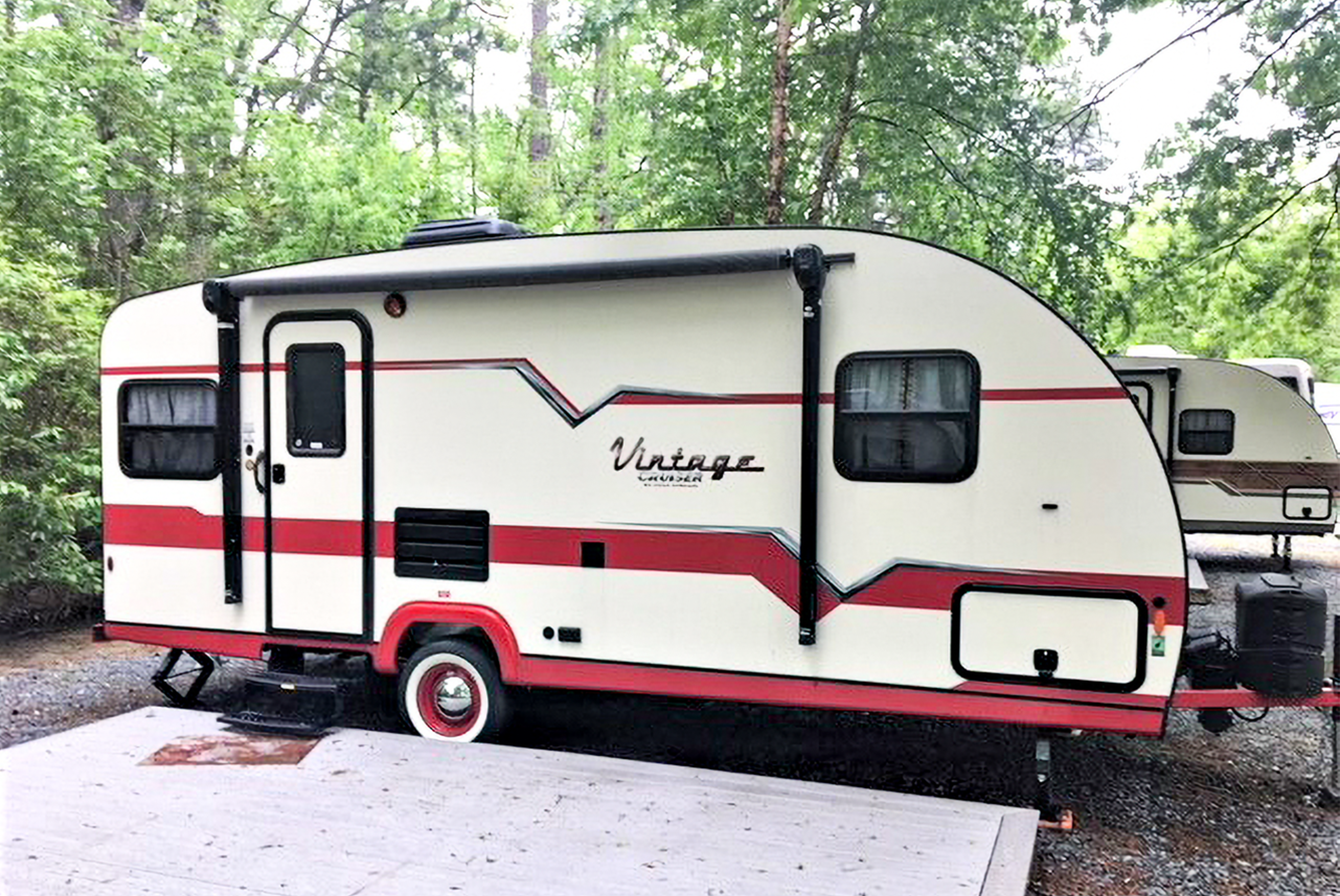 The trailer's exterior with a wooden deck, picnic table, and fire ring.